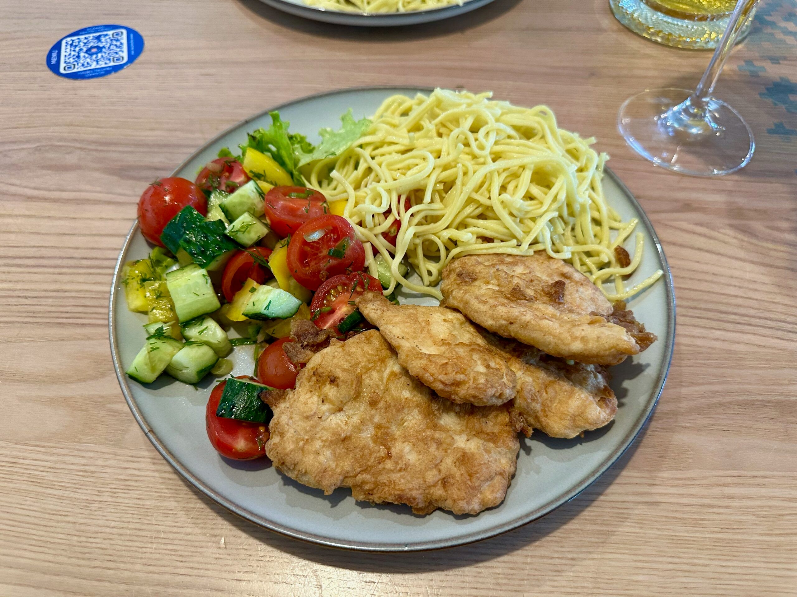 Moldova, chisinau foods plate with spaghetti, fried cutlets, and a cucumber and tomato salad on a wooden table