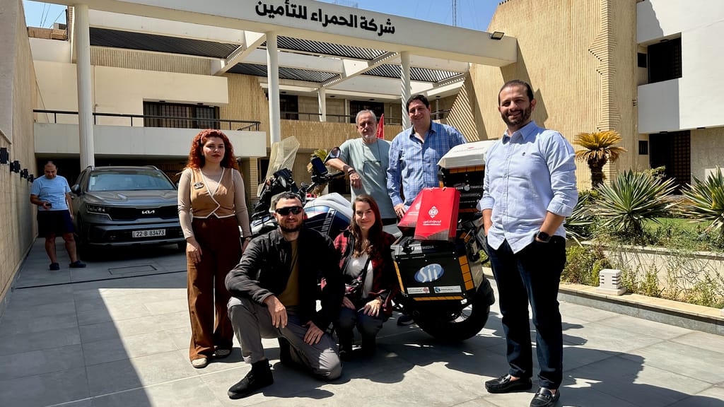 Grupa osób przy motocyklu przed budynkiem firmy al hamra w bagdadzie.