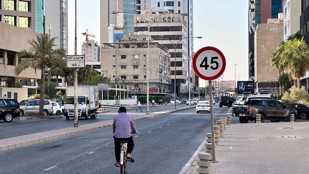 Ulica w kuwait city road z rowerzystą i nowoczesnymi wieżowcami w tle