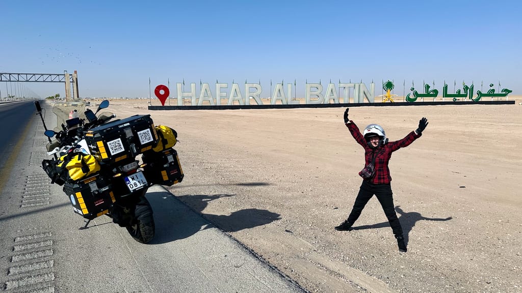 Hafar al batin road w arabii saudyjskiej, motocyklista obok znaku miejscowości i drogi.