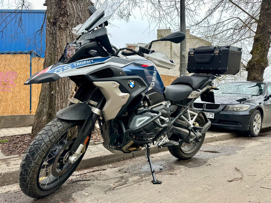 Bmw r1250 gs trophy z kufrem, zaparkowany przy ulicy.
