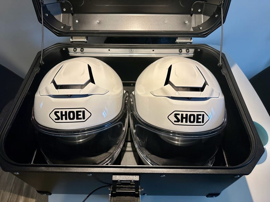 Dwa białe kaski shoei w otwartym kuferku motocyklowym.