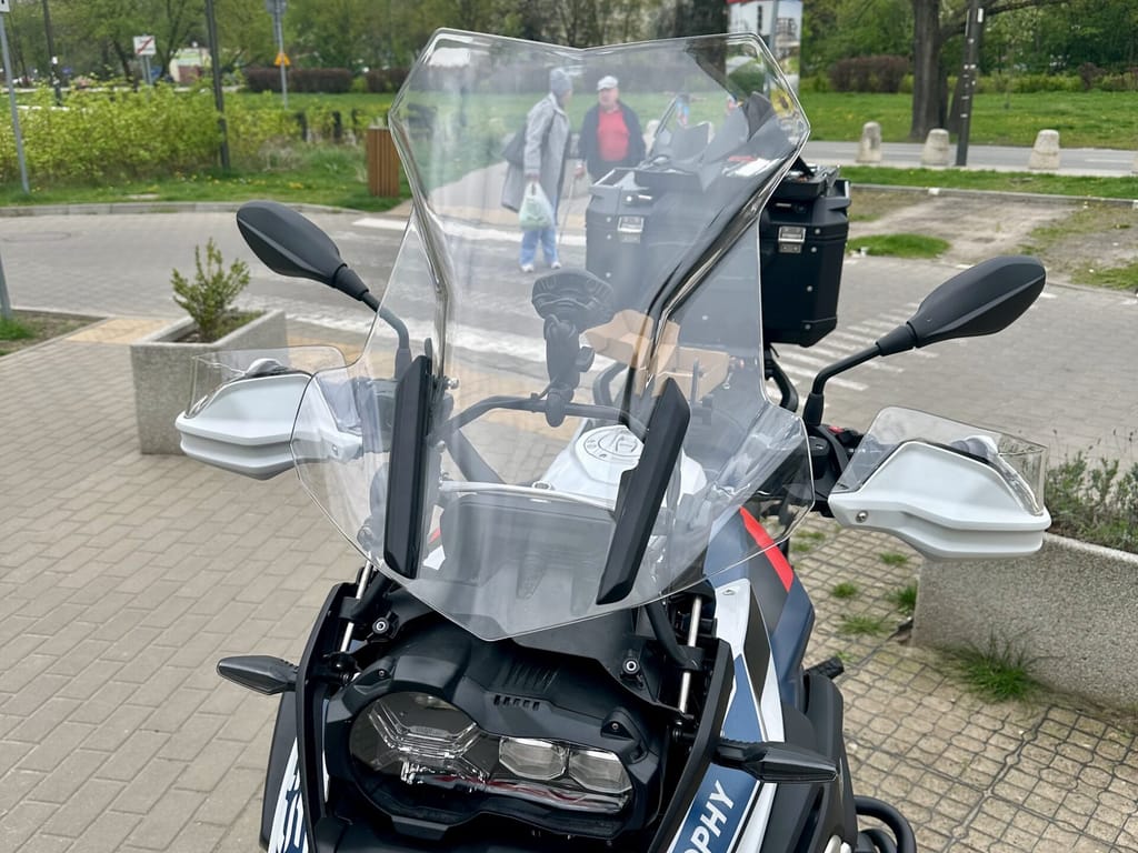 Motocykl bmw r1250gs trophy zaparkowany przy chodniku w parku miejskim