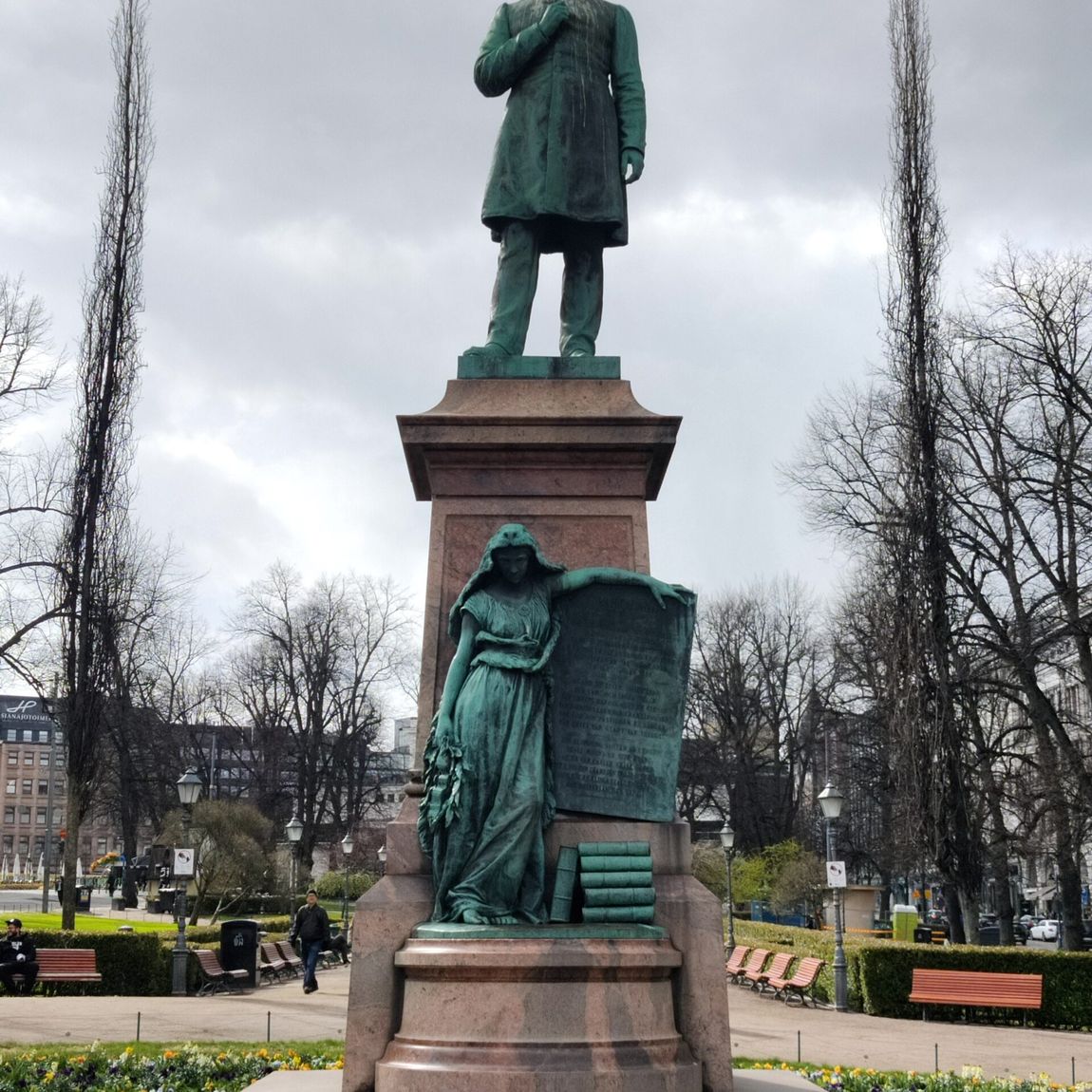 Pomnik na esplanadi w helsinkach z zieloną rzeźbą i kwiatami u podstawy