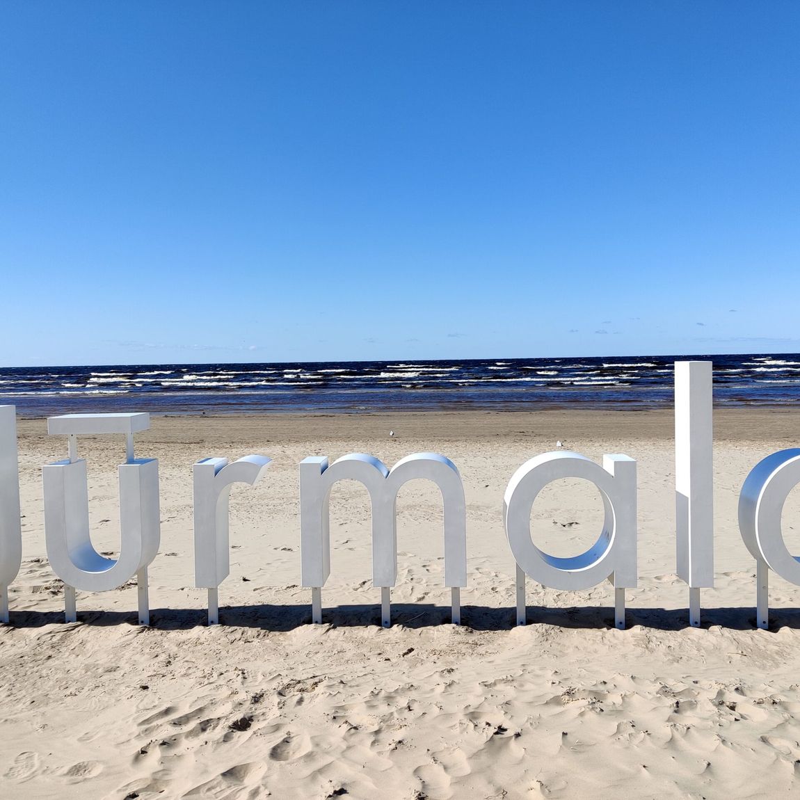 Napis jurmala na piaszczystej plaży nad morzem.