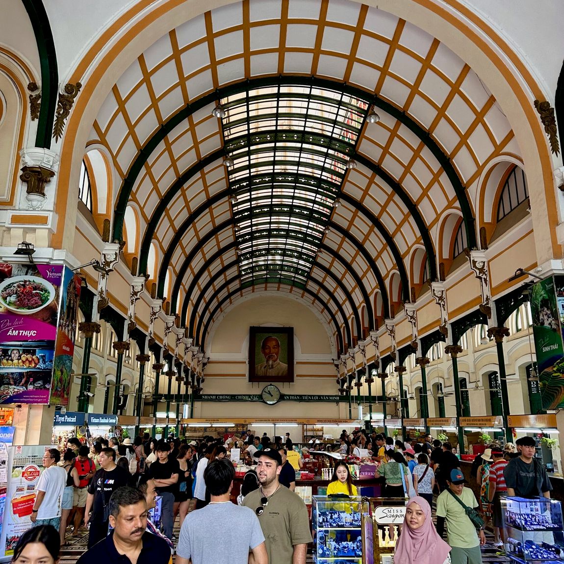 Wnętrze ho chi minh post office z tłumem turystów i stoiskami z pamiątkami.