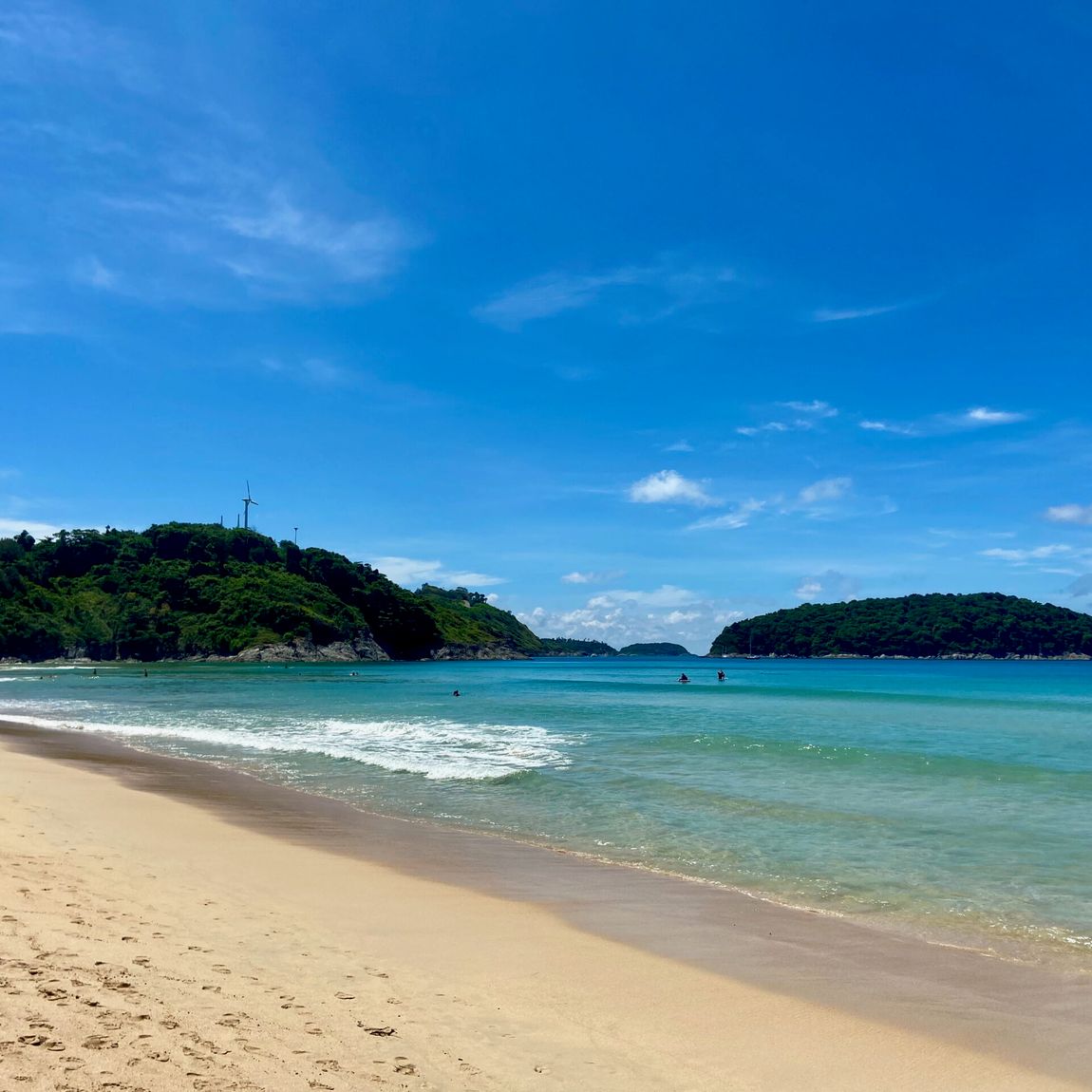 Plaża w phuket w tajlandii z turkusową wodą, żółtym piaskiem i zielonymi wzgórzami w tle