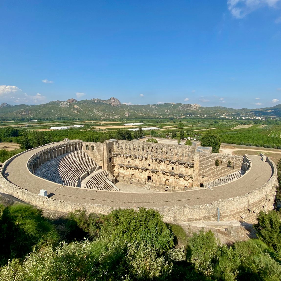 Amfiteatr aspendos na lazurowym wybrzeżu turcji z widokiem na zieloną dolinę i góry.