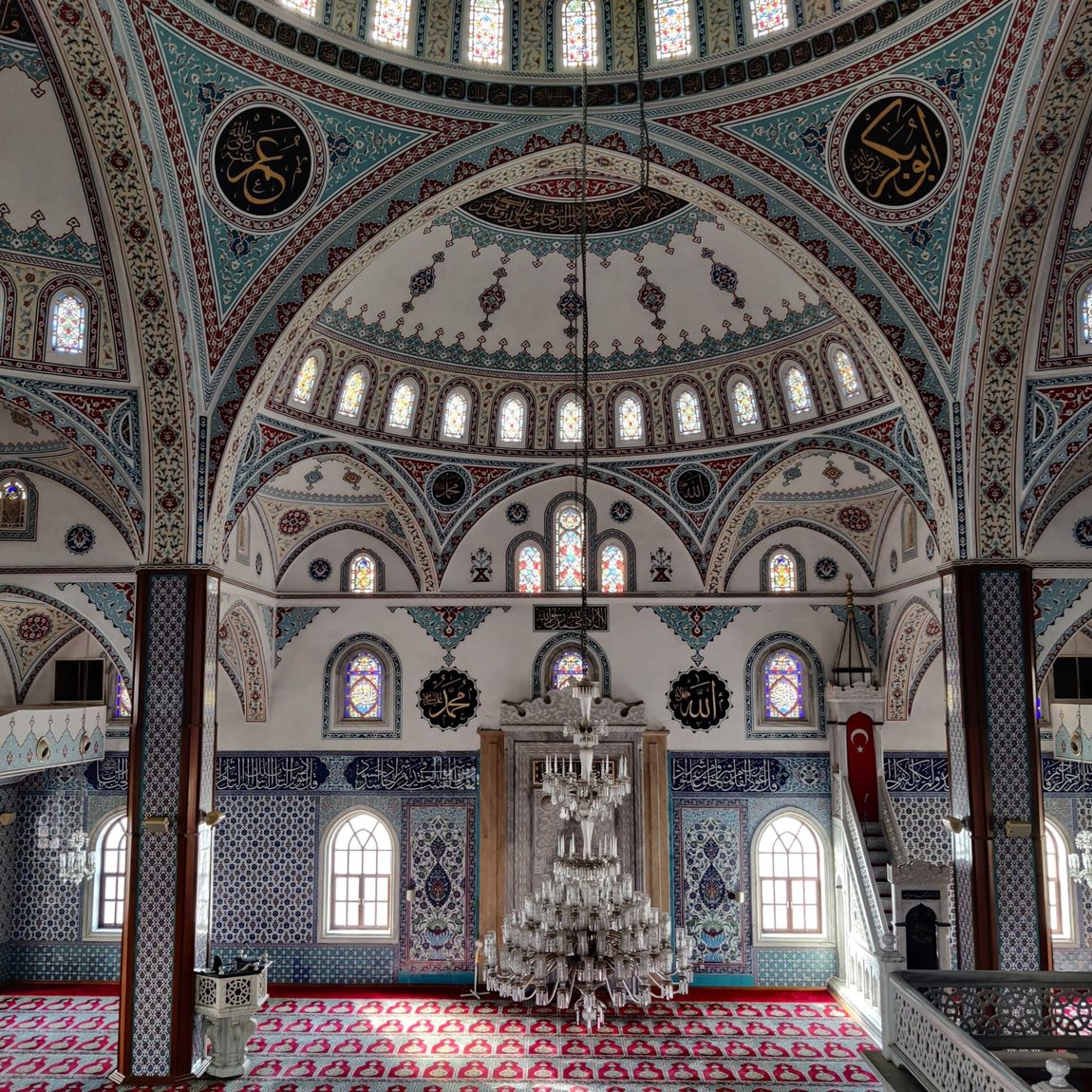 Wnętrze meczetu cami w manavgat na tureckiej riwierze, z kolorowymi mozaikami i żyrandolem.