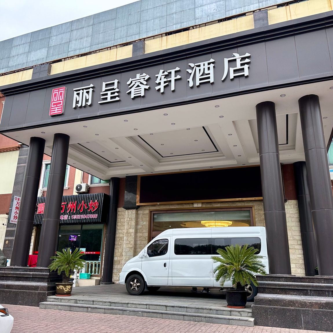 Wejście do hotelu shanghai hotel z chińskim szyldem i białym vanem na podjeździe