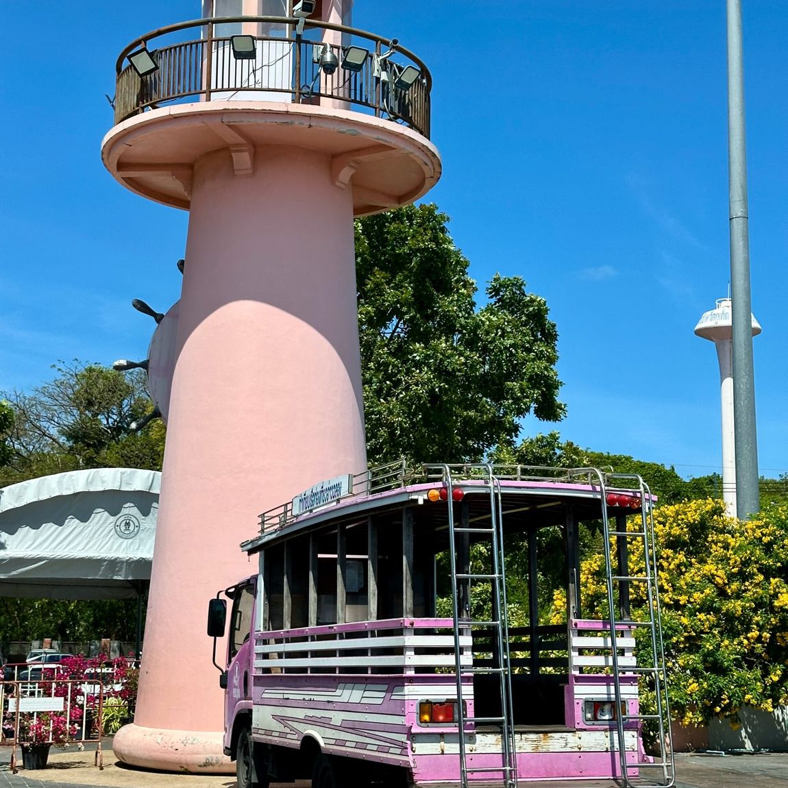 Phuket chalong pier: różowa latarnia morska i mały autobus pod błękitnym niebem.