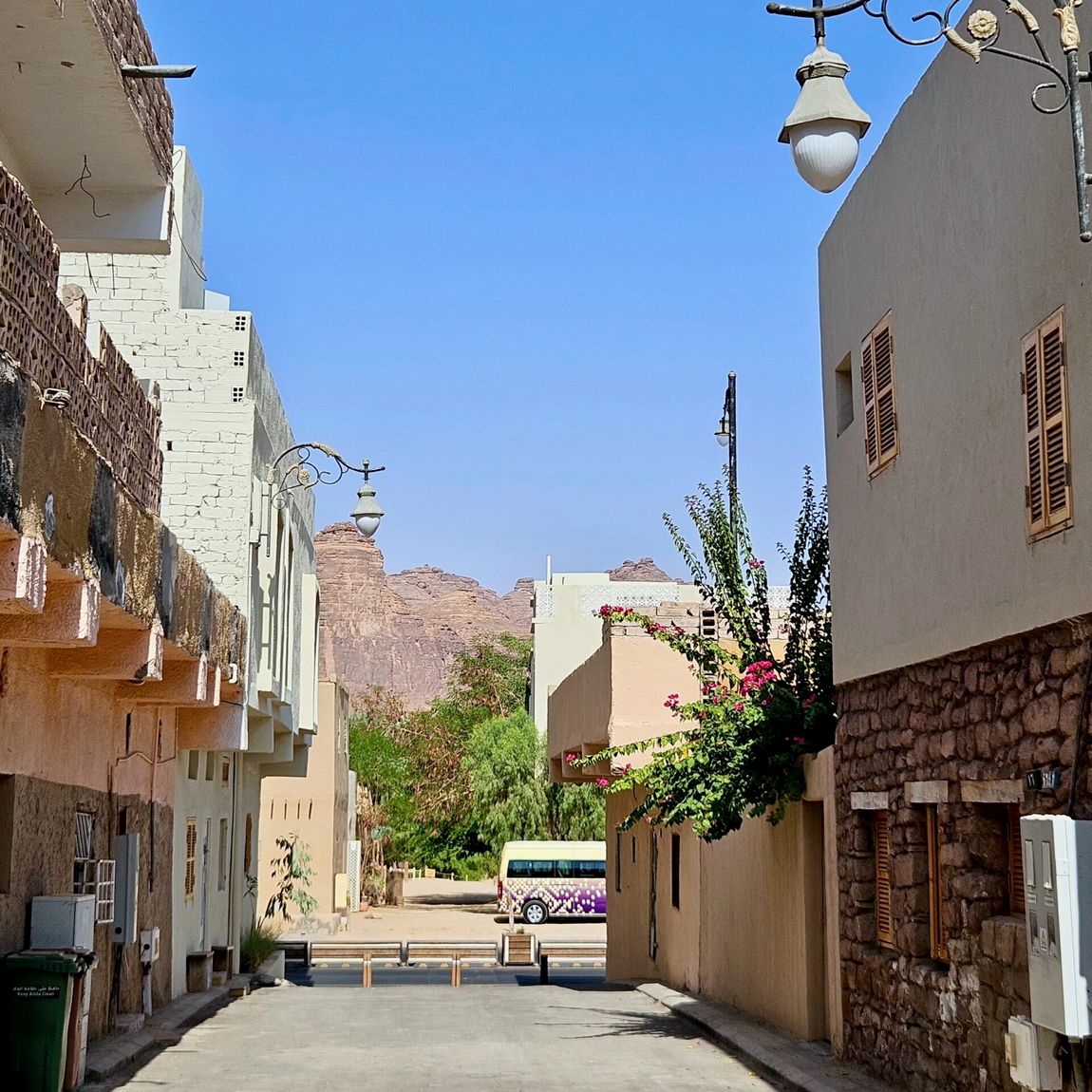 Al ula, saudi arabia street view with traditional buildings, hanging lanterns, and desert cliffs in the distance