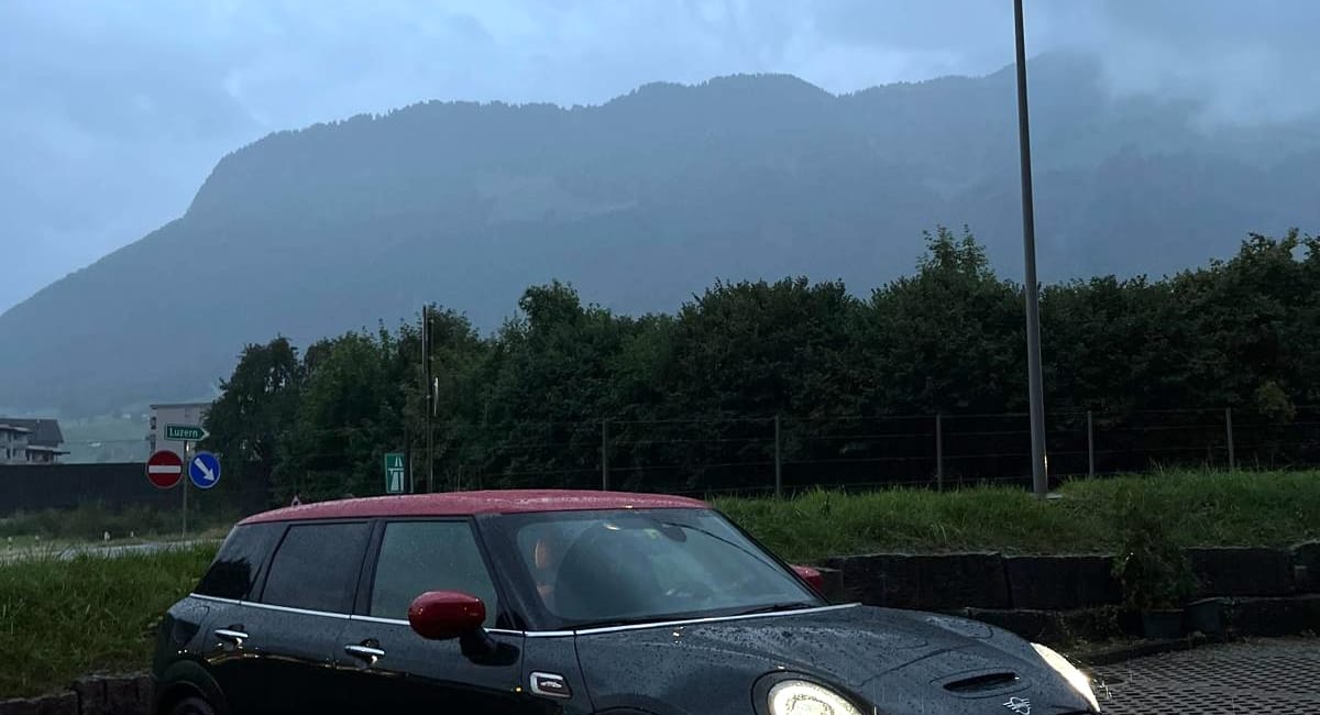 Samochód mini w interlaken w szwajcarii, zaparkowany przy drodze w deszczu o zmierzchu.