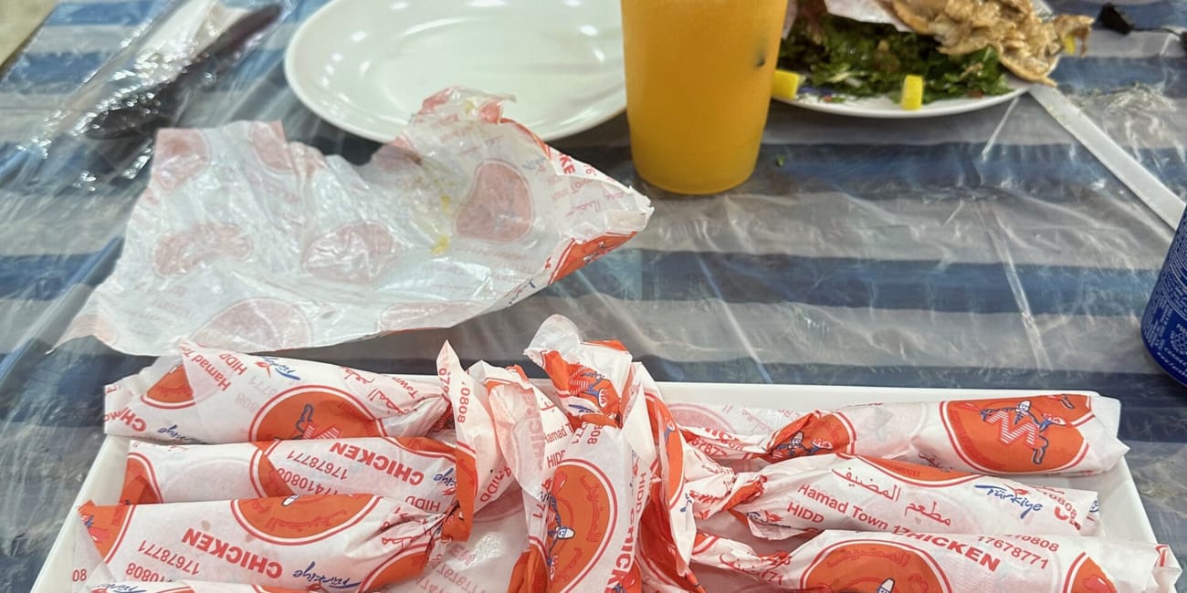 Posiłek w bahrainie: tacka z zawiniętymi kanapkami i sokiem przy stole w restauracji.