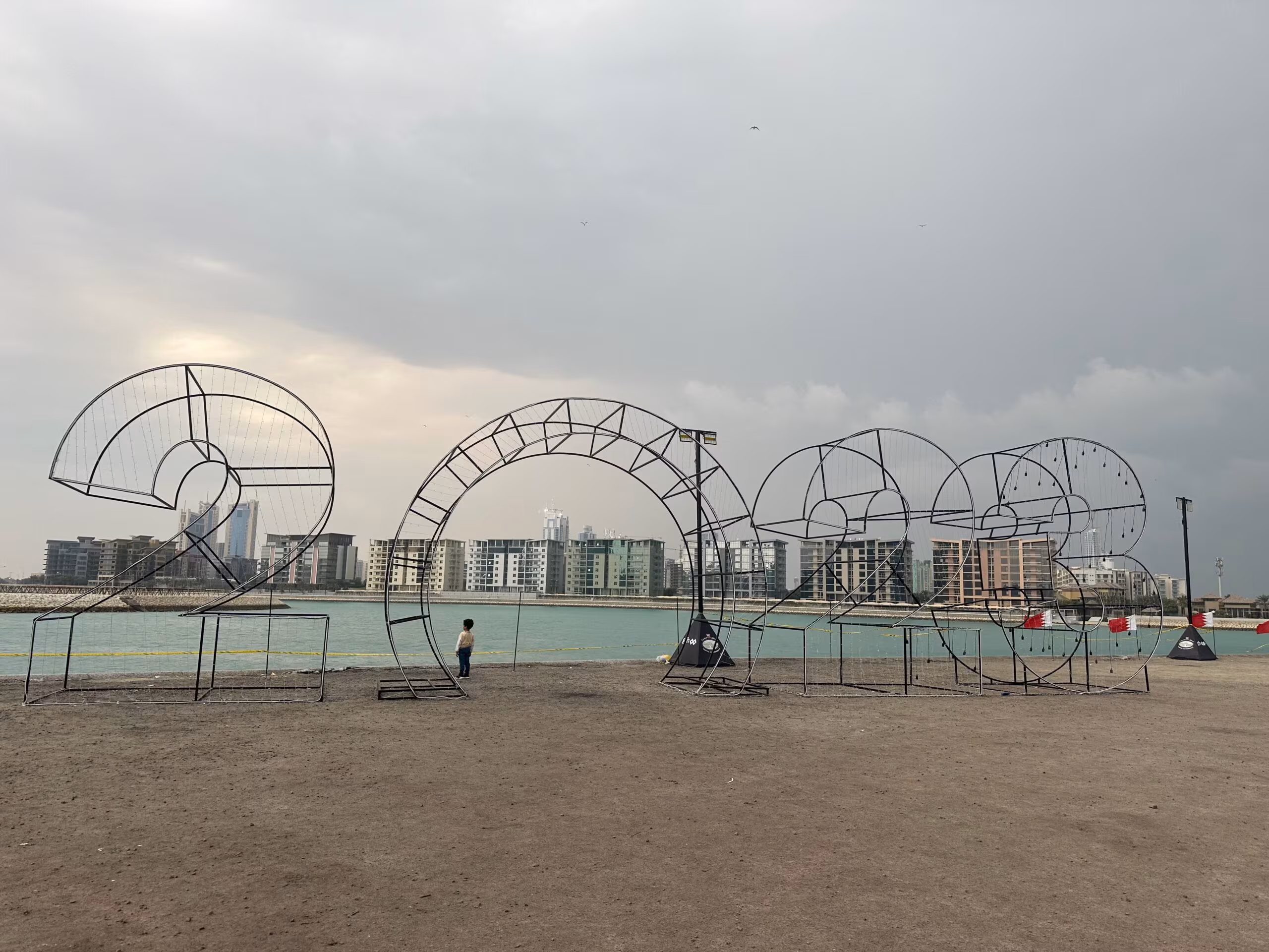 Napis 2023 na plaży w bahrajnie nad wodą z miejską panoramą w tle