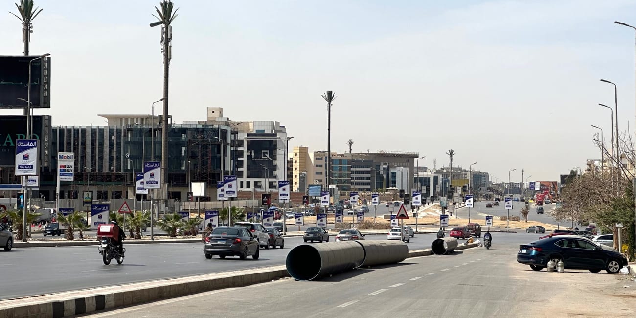 Road construction on a wide egyptian boulevard with traffic and road signs.
