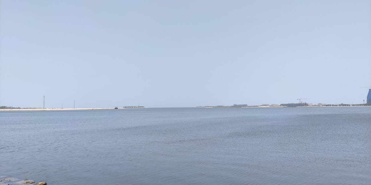 Dammam corniche w arabii saudyjskiej: spokojna zatoka, kamienisty brzeg i jasne niebo