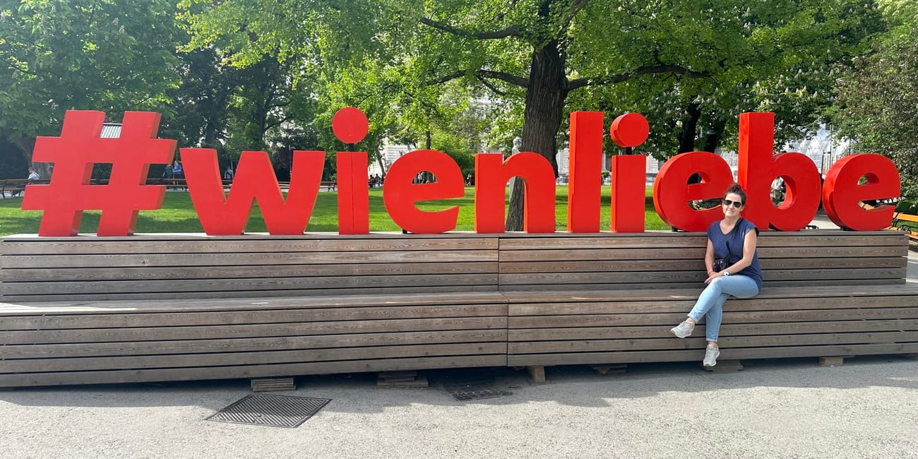 Czerwony napis #wienliebe w parku w wiedniu, obok siedzi kobieta.