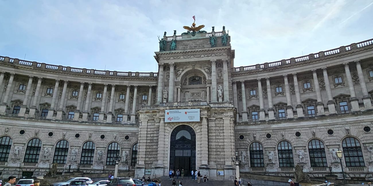 Hofburg w wiedniu z okazałą fasadą i dziedzińcem pełnym samochodów oraz pieszych