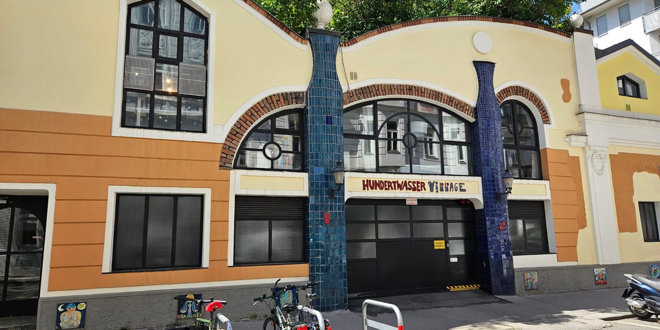 Hundertwasser village w wiedniu z kolorową, falującą fasadą i rowerami przed wejściem