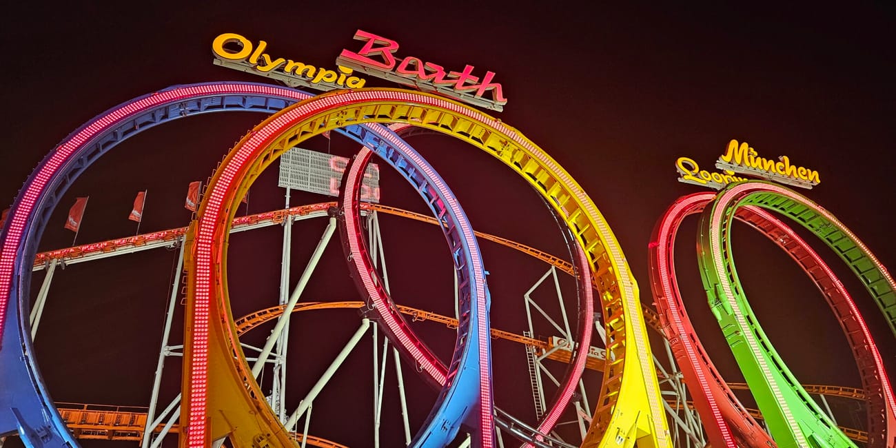 Kolejka górska olympia looping w vienna prater nocą, z kolorowymi pętlami i neonowymi napisami miast.