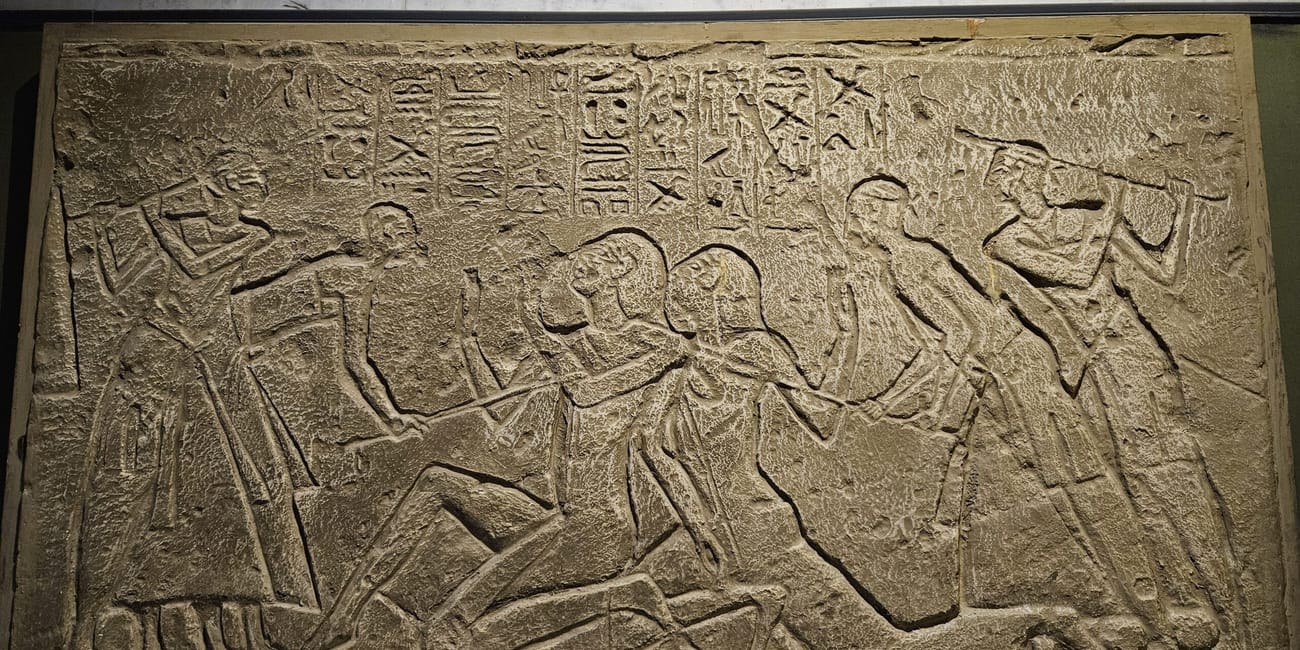 Relief w cairo national military museum z przedstawieniem kilku postaci i hieroglifów.