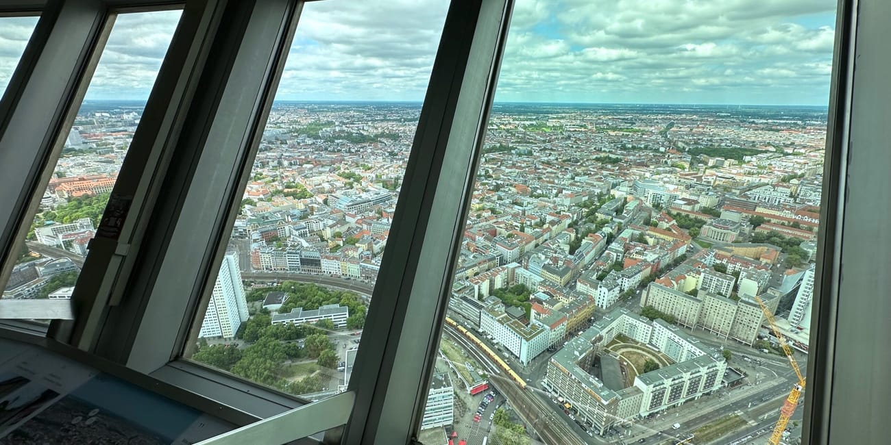 Panorama berlina z tarasu widokowego, widok przez duże okna na rozległe miasto i zachmurzone niebo