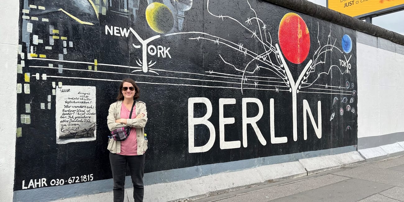 Kobieta stoi przy murze berlińskim z muralem berlin.
