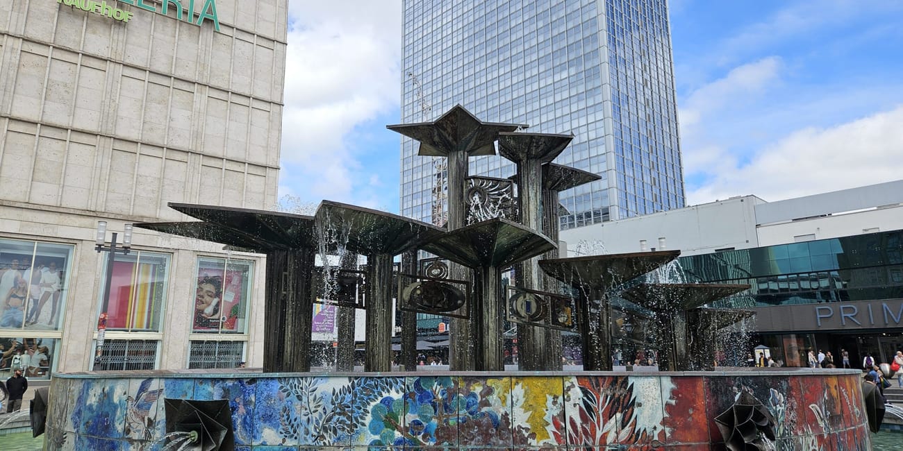Fontanna przy galerii kaufhof na alexanderplatz w berlinie, z wieżowcem w tle
