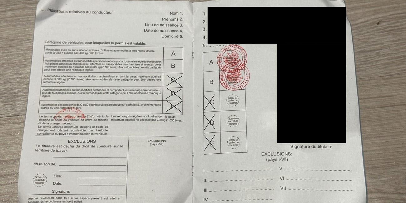 Rozłożony międzynarodowy dokument prawa jazdy z pieczęciami i tabelą kategorii pojazdów.