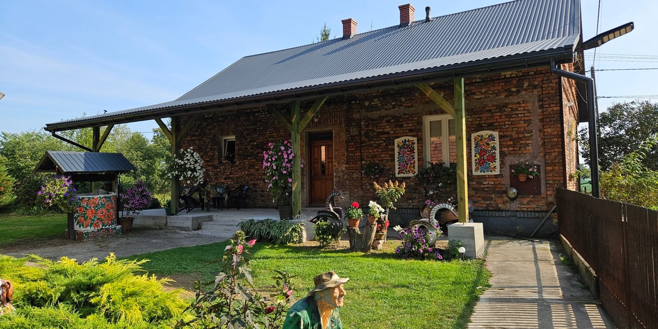 Dom w zalipiu ozdobiony kwiatowymi malowidłami i figurami w ogrodzie.