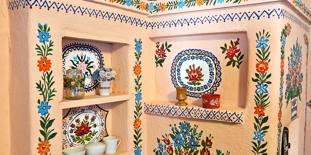 Malowana izba w gospodarstwie felicji curylowej w zalipiu, z kwiatowymi zdobieniami i ceramiką.