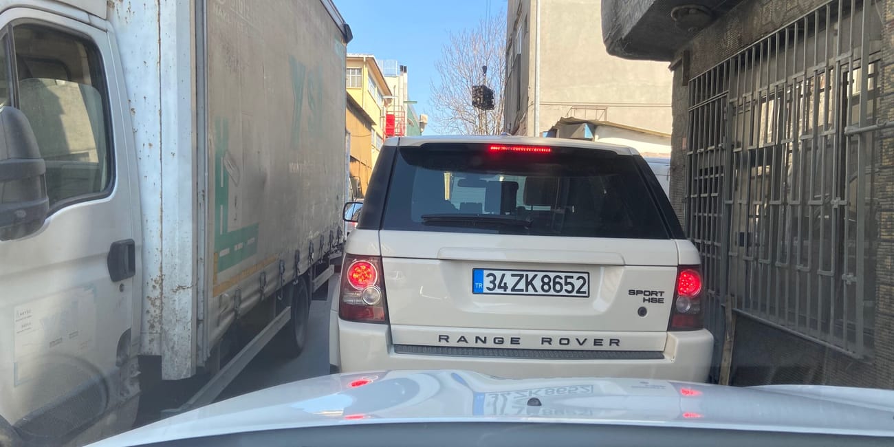 Range rover stoi w wąskiej uliczce w turcji między ciężarówkami.