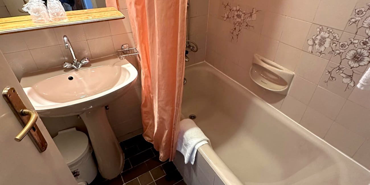 Łazienka hotelowa w budapeszcie z wanną, umywalką i różową zasłoną prysznicową