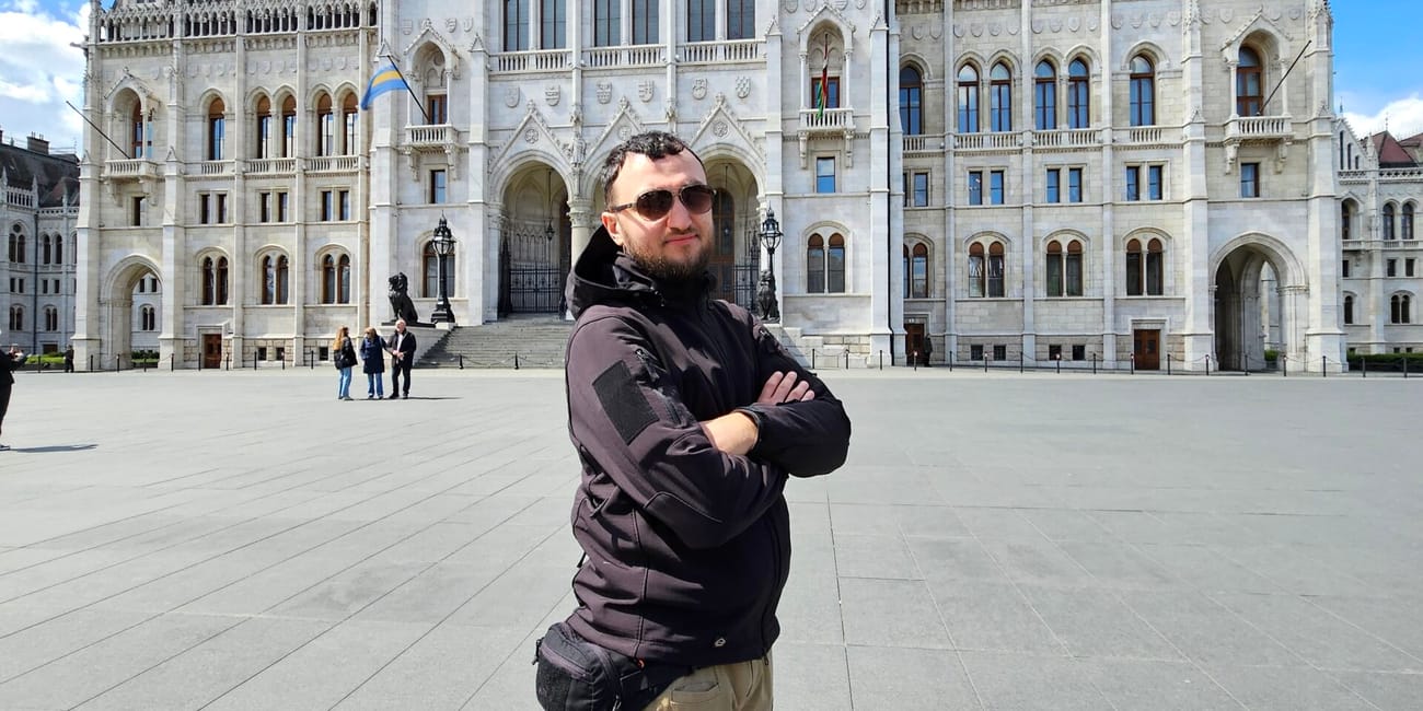 Mężczyzna stoi przed budynkiem parlamentu w budapeszcie.