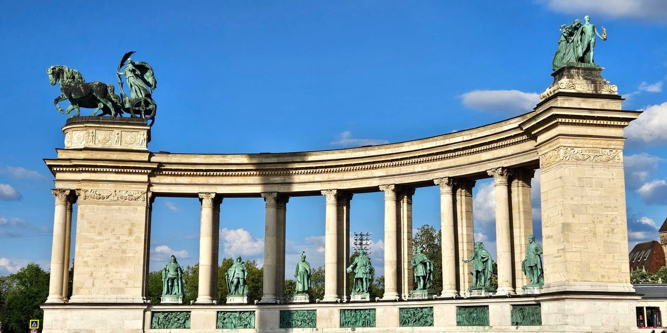 Plac bohaterów w budapeszcie z półkolistą kolumnadą i posągami pod błękitnym niebem