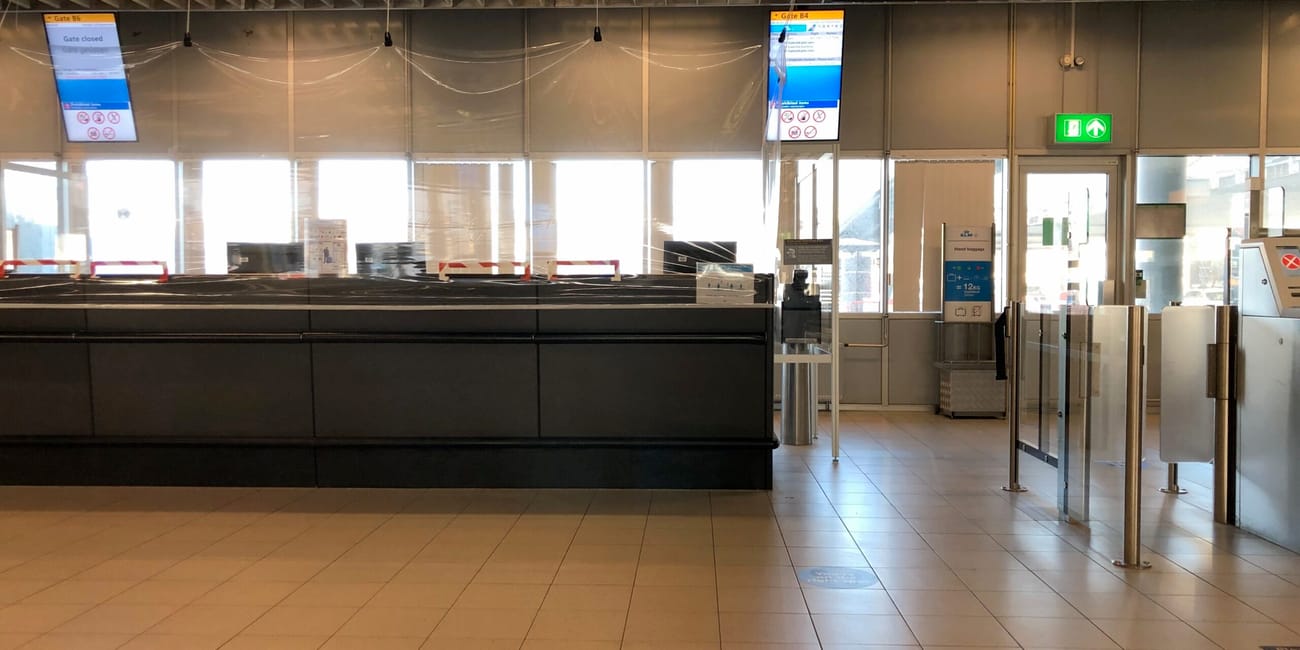 Zamknięta strefa bramek na lotnisku amsterdam airport z komunikatami o pozostaniu na miejscach