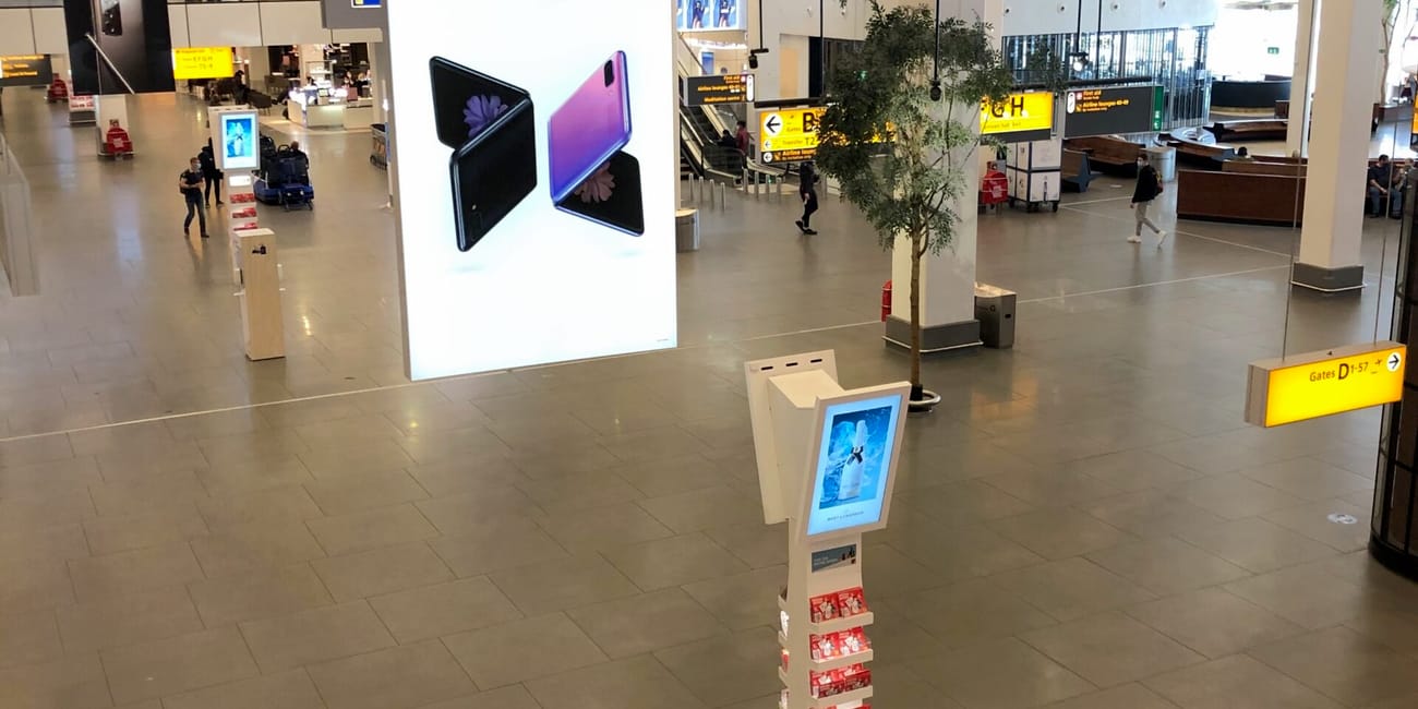 Hol główny lotniska amsterdam airport z dużą reklamą samsung galaxy z flip i tablicami kierunkowymi