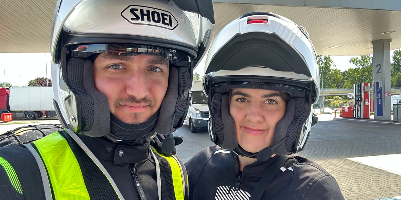 Dwoje motocyklistów w kaskach robi selfie na stacji benzynowej w szczecinie.