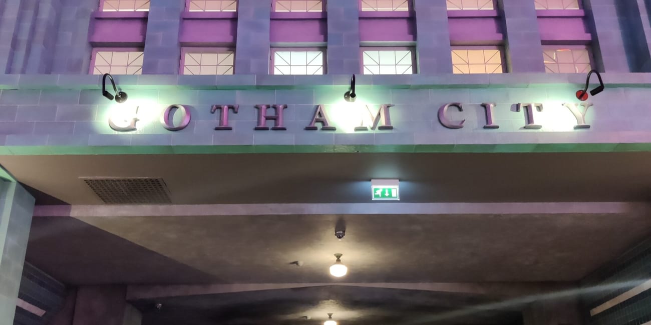 Wejście do gotham city w warner bros w abu dhabi z podświetlonym szyldem i uliczką w stylu komiksowym.