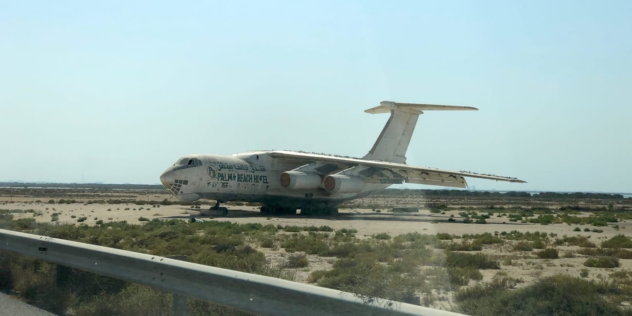 Samolot w umm al quwain, uae, stojący na pustynnym terenie przy drodze.
