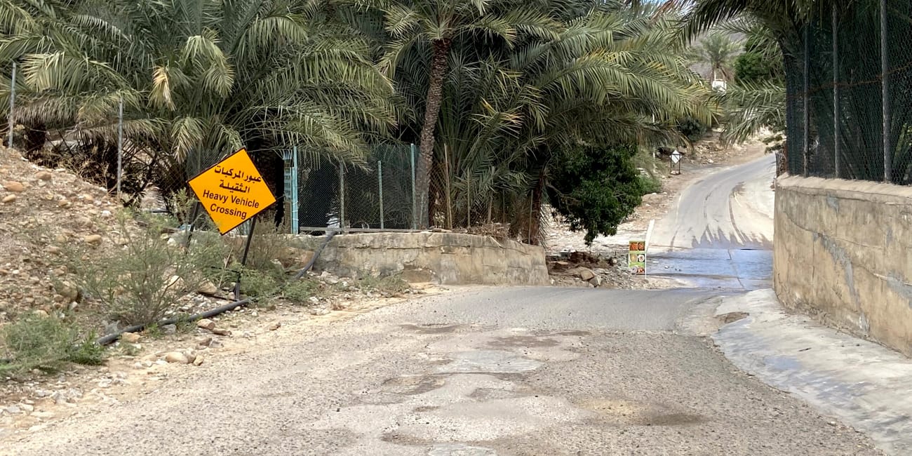 Droga wśród palm w fujarjah z żółtym znakiem „heavy vehicle crossing”