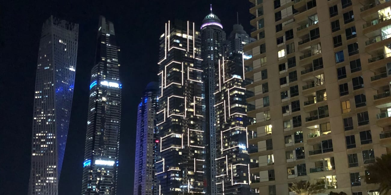 Wieżowce dubaju nocą, oświetlone linie na fasadach i ruch uliczny poniżej