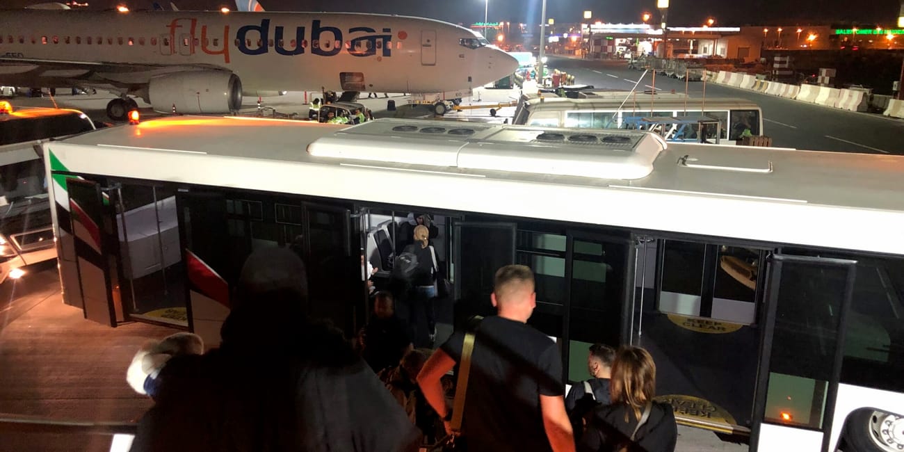 Pasażerowie schodzą po schodach do autobusu przy samolocie flydubai na lotnisku w dubaju nocą