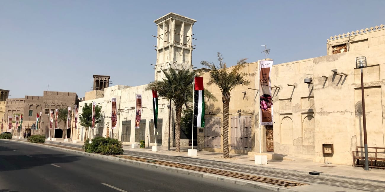Tradycyjne zabudowania w dubaju z wieżą wiatrową i flagami przy ulicy