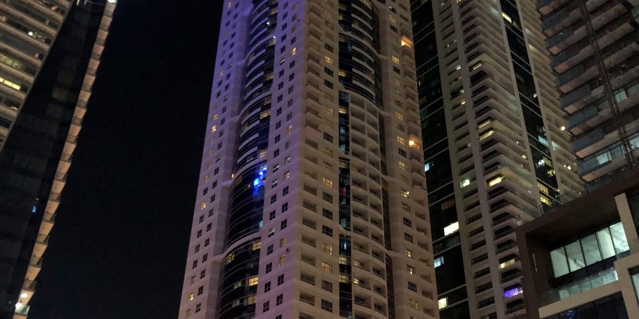 Wieżowiec marriott w dubaju nocą, otoczony innymi wysokimi budynkami.
