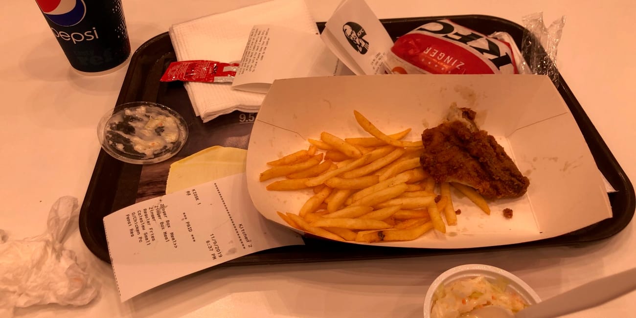 Posiłek w kfc w dubaju: kurczak, frytki, pepsi i dodatki na tacy.
