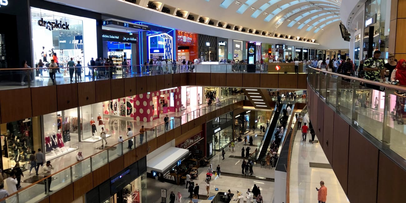 Wnętrze centrum handlowego w dubaju z kilkoma poziomami sklepów i ruchomymi schodami.