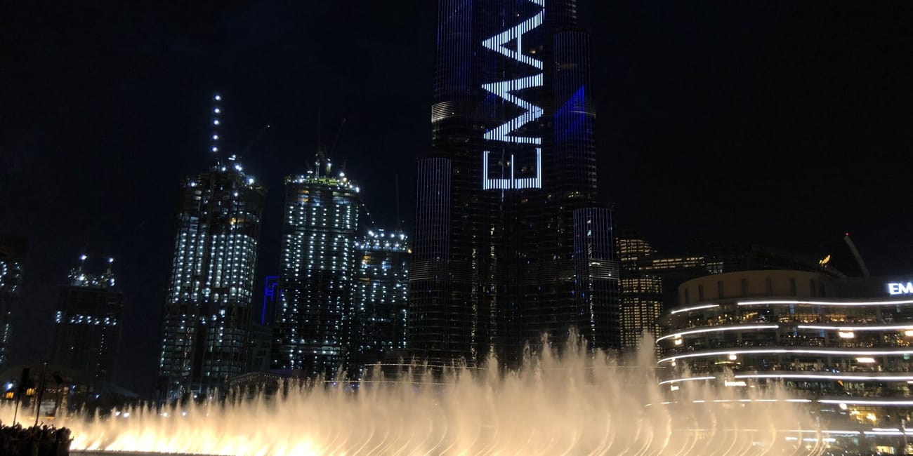 Dubai fountain z pokazem wody przed wieżowcem emaar w dubaju nocą
