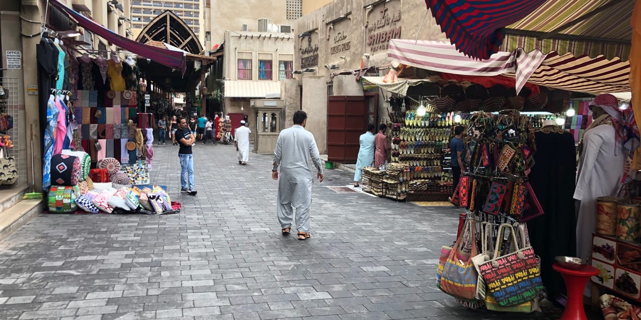 Targ na suku w dubaju z kolorowymi straganami i przechodniami.
